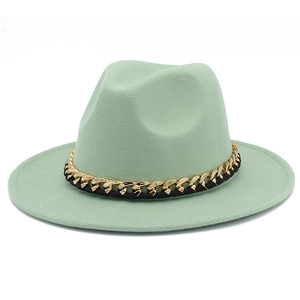 Détail d'un chapeau fedora vert menthe avec chaîne en métal doré et ruban tressé noir