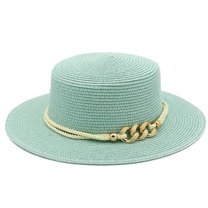 Detail of mint green straw boater hat featuring gold chain link and twisted rope trim