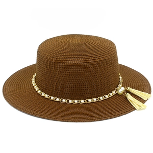 Dettaglio cappello di paglia marrone con catena dorata, perle e nappine decorative