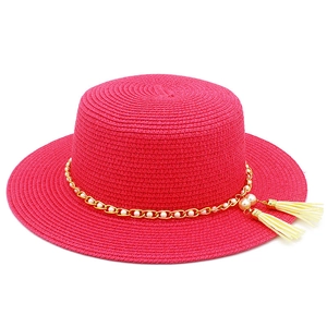 Dettaglio cappello di paglia fucsia con catena dorata e nappa di perle decorativa