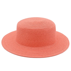 Dettaglio della trama del cappello di paglia rosa corallo a tesa larga per il sole estivo