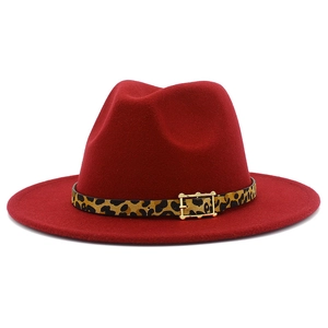 Detail of red fedora hat featuring leopard print band and gold buckle on white background