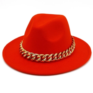 Macro detail of red wool fedora hat featuring a stylish bold gold cuban chain band