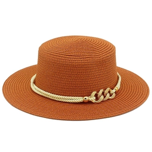 Detailed close-up of orange boater hat with cream rope and golden chain buckle