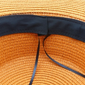 Detail of orange straw hat interior featuring black sweatband and adjustable drawstring