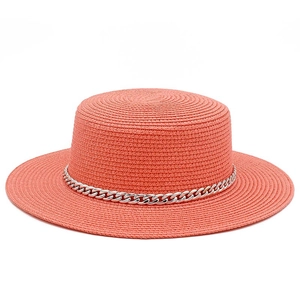 Detail of coral orange flat top straw hat with decorative chunky silver metal chain link