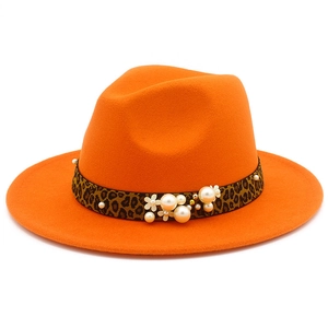 Detail of orange wide brim fedora hat featuring leopard print band with white pearls