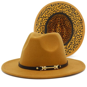 Détail d'un chapeau fedora jaune avec bord imprimé léopard et ceinture en cuir noir