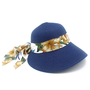 Detail van blauwe strohoed met brede rand en geel hibiscus bloemenlint strik