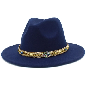 Close-up of navy blue wool fedora hat with ornate gold woven band and blue gemstone details