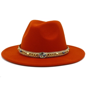 Détail d'un chapeau en laine orange avec chaîne dorée, perles bleues et décorations