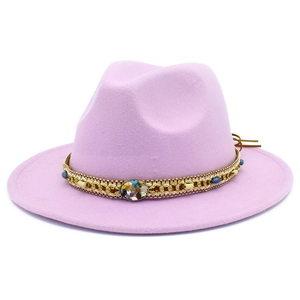 Détail d'un chapeau fedora rose avec ruban tressé ethnique et gemme arc-en-ciel