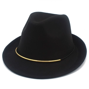 Detailaufnahme der goldenen Metallverzierung an einem schwarzen Fedora-Filzhut