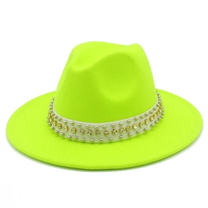 Détail d'un chapeau fedora vert néon avec bande blanche, clous dorés et strass brillants