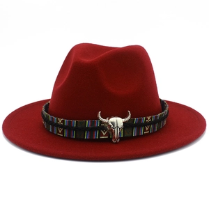 Détail du chapeau fedora bordeaux avec ruban ethnique et ornement de crâne de taureau argenté