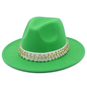 Détail d'un chapeau fedora vert vif avec ruban blanc, clous argentés et strass dorés