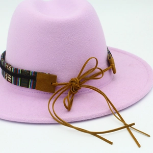 Détail d'un chapeau en feutre rose avec ruban ethnique et cordon en daim marron