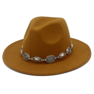 Detailed view of brown fedora hat with vintage silver metal chain and bohemian carvings