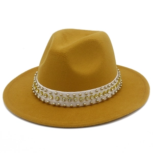 Vue détaillée d'un chapeau fedora jaune moutarde avec ruban orné de perles et strass