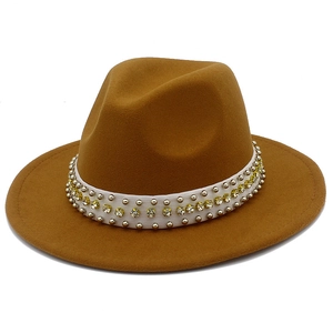 Détail d'un chapeau fedora en laine marron avec ruban blanc, rivets argentés et strass jaunes