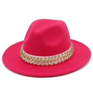 Détail d'un chapeau fedora rose avec ruban de perles, rivets argentés et strass jaunes