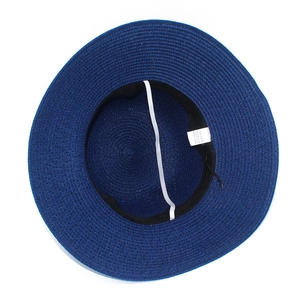 Detail view of the woven paper straw hat interior with elastic strap and care label