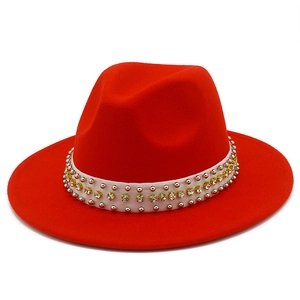 Détail du chapeau fedora rouge avec clous argentés et strass jaunes sur ruban blanc