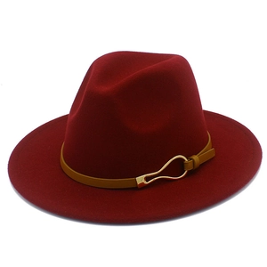 Detail of burgundy wool fedora hat featuring a brown leather band and gold metal buckle