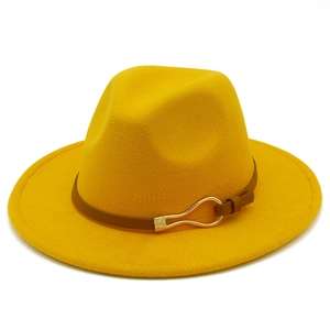 Detail of yellow fedora hat with brown leather band and gold buckle on white background
