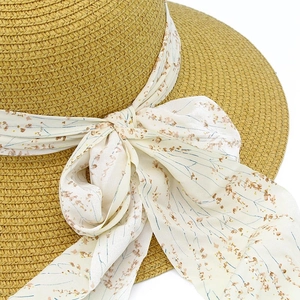 Detail of woven straw sun hat featuring a floral ribbon tied in a delicate bow knot