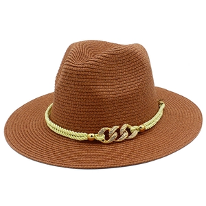Detail of woven straw texture on brown Panama hat with a decorative gold chain buckle