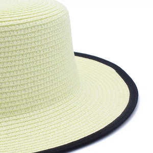 Détail du chapeau de paille à sommet plat avec texture tissée et bordure en tissu noir