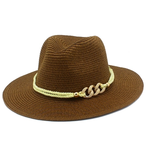 Detailed view of brown straw Panama hat with yellow rope and gold chain link decoration