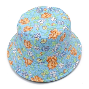 Détail d'un chapeau de soleil en coton avec fleurs orange sur un fond bleu clair