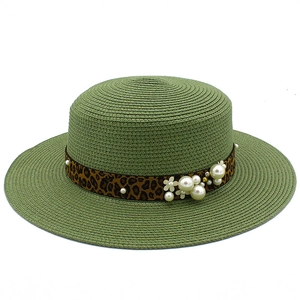 Detailed texture of green straw boater hat with leopard ribbon and pearl accents