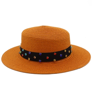 Détail d'un chapeau canotier orange en paille avec ruban noir orné de strass colorés