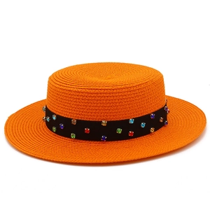 Détail d'un chapeau canotier orange en paille avec ruban noir et strass multicolores