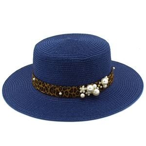 Detailed close-up of navy straw hat with leopard print band and pearl floral accents