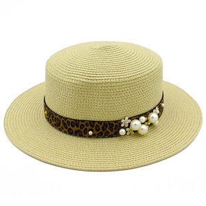 Close-up of woven straw hat with leopard print ribbon and faux pearl embellishments