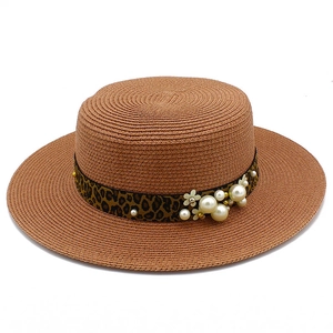 Close-up of leopard print ribbon with pearl accents on a stylish straw boater sun hat