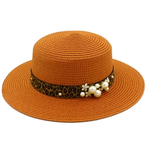 Detail of orange straw boater hat with leopard print ribbon and pearl floral accents