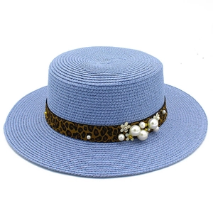 Detail of blue boater straw hat with leopard print ribbon and decorative pearls