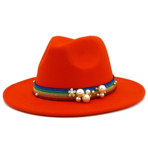 Close-up of orange wool fedora hat with rainbow ribbon, pearls, and a small flower detail