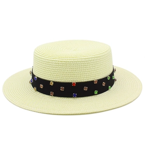 Détail d'un chapeau de paille à haut plat avec ruban noir et pierres précieuses
