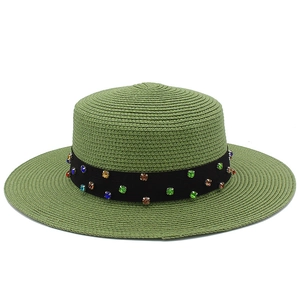 Détail du chapeau de paille vert avec ruban noir orné de strass multicolores
