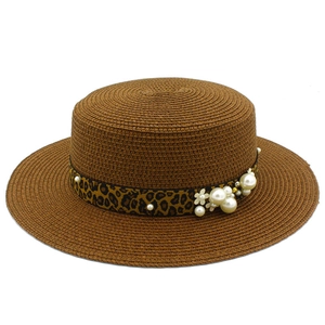 Detail of straw hat with leopard print band and pearl floral accents in close-up view