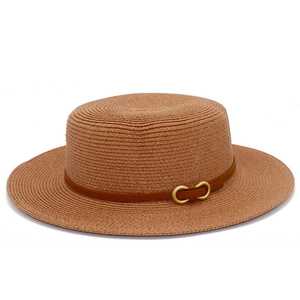 Détail d'un chapeau en paille avec lanière en cuir brun et boucle dorée élégante