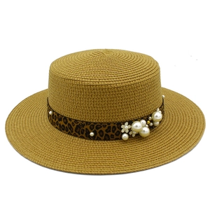 Detail of khaki straw hat featuring leopard print ribbon, white pearls and floral accents