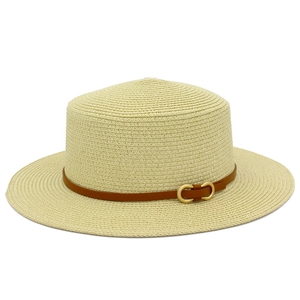 Détails de la texture d'un canotier crème avec ruban en cuir marron et boucle dorée