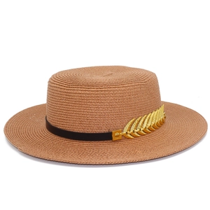 Detail of flat top straw hat with black band and gold leaf metallic ornament